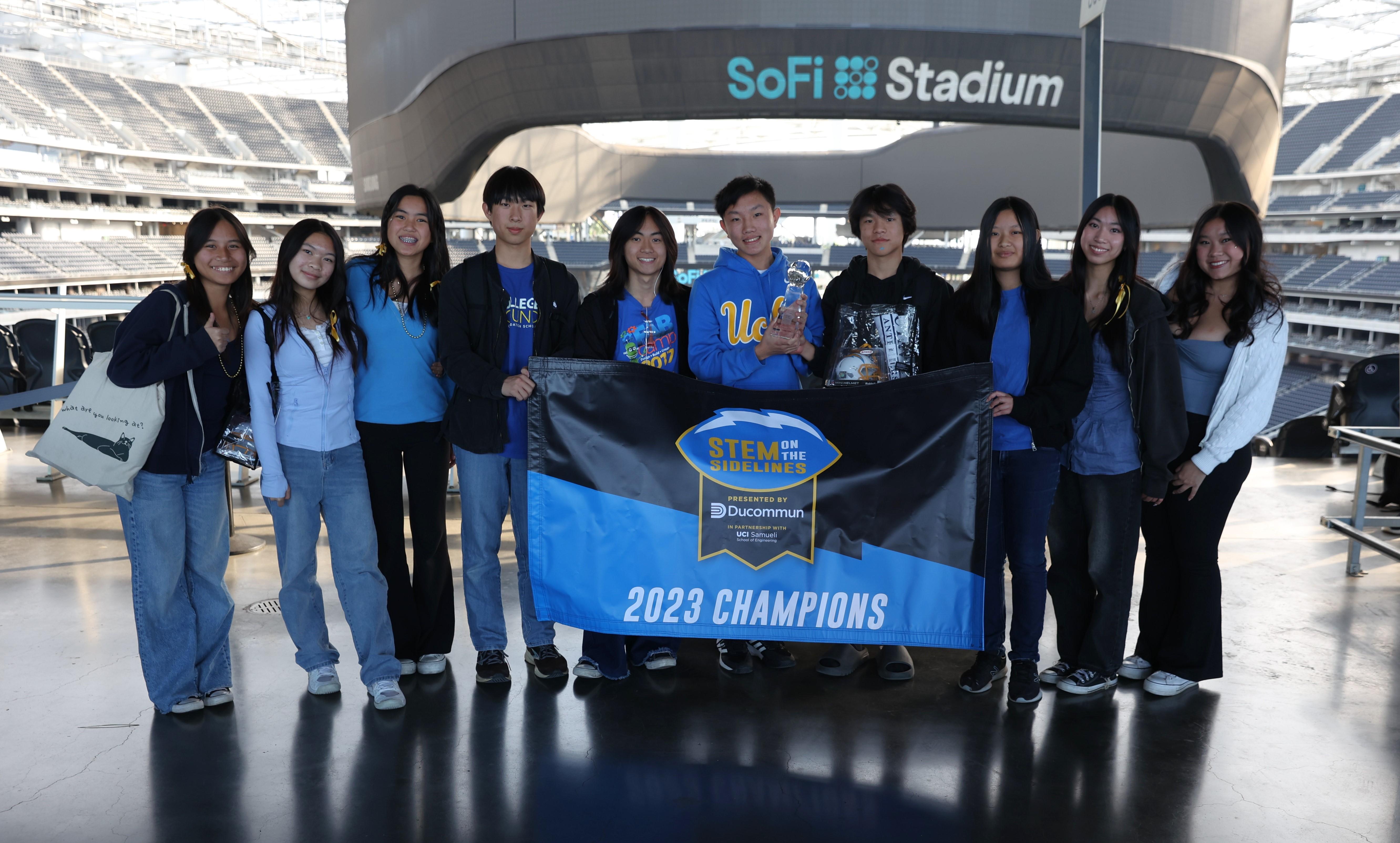 Robotics team pose with their trophy at SoFi Stadium